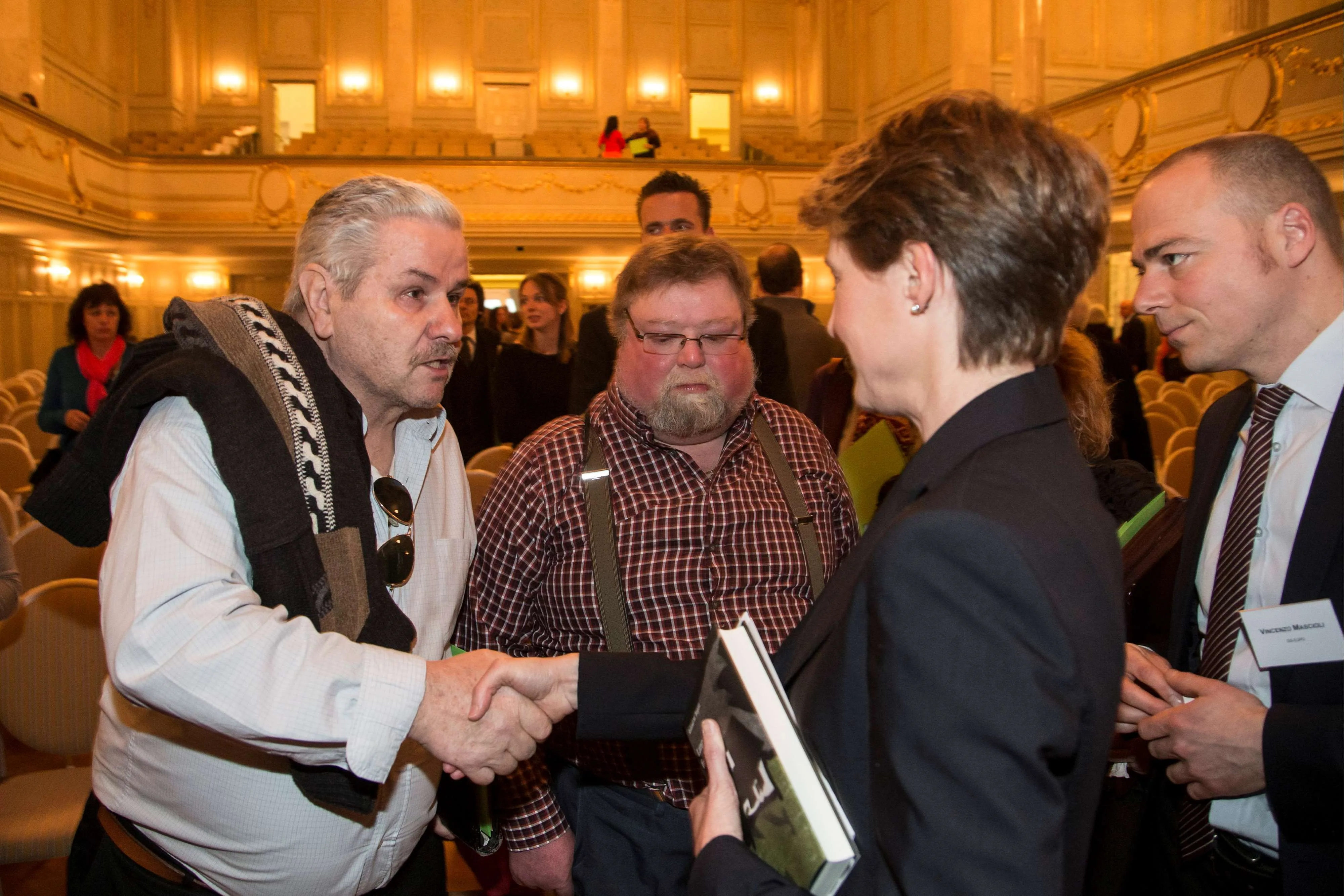Les personnes concernées discutent avec la conseillère fédérale Simonetta Sommaruga lors de la cérémonie commémorative en hommage aux victimes de mesures de coercition à des fins d'assistance, le jeudi 11 avril 2013 à Berne. La ministre de la Justice Simonetta Sommaruga a présenté ses excuses aux personnes concernées au nom du Conseil fédéral. Jusque dans les années 60, les orphelins et les enfants de familles pauvres étaient placés chez des paysans, où ils devaient travailler dur en échange du gîte et du couvert. De nombreuses personnes concernées font état de graves mauvais traitements et d'arbitraire de la part des autorités.